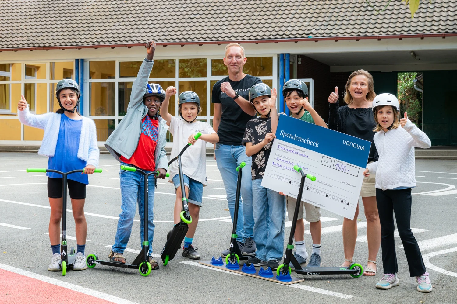Vonovia Quartiersentwickler Sascha Stumm (Mitte) übergibt den Spendenscheck über 1.500 Euro an Tatjana Trippler (rechts) und die Schülerinnen und Schüler der Sonnenschule in Bochum-Weitmar. Beitrag: Vonovia fördert Verkehrserziehung an der Sonnenschule